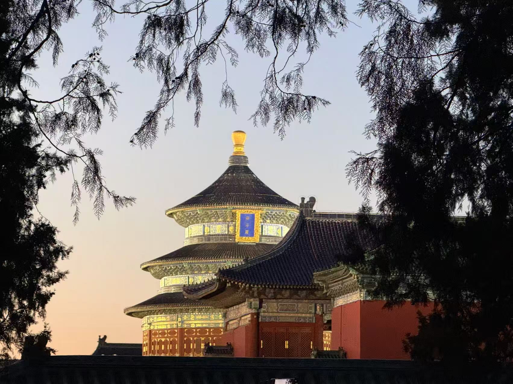 天坛傍晚，祈年殿在树影和晚霞中亮灯